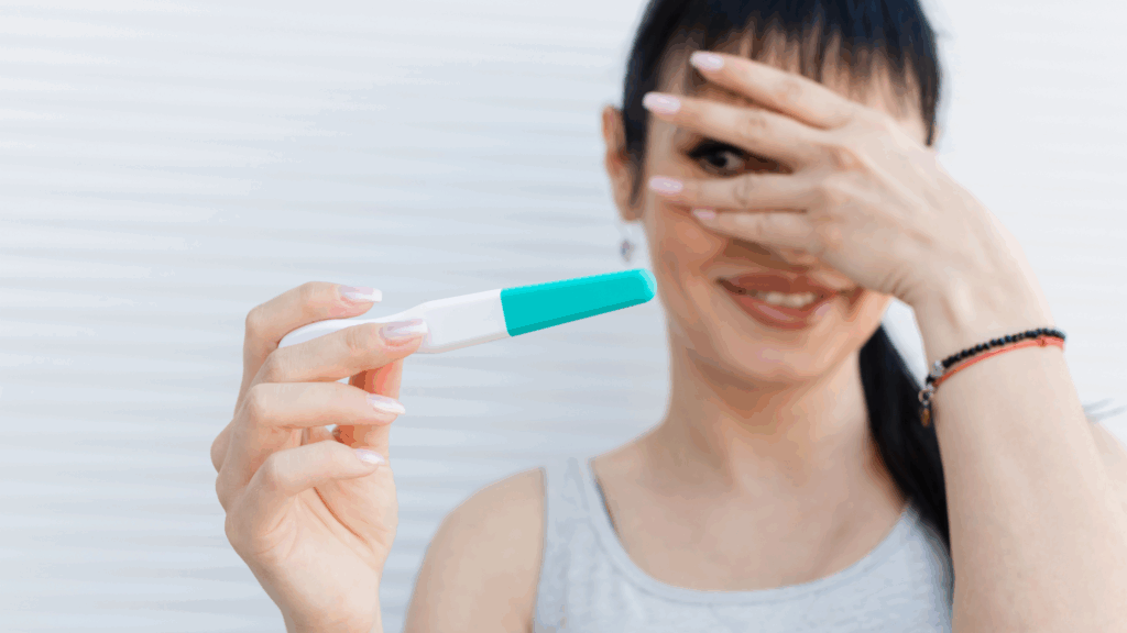 Mulher segurando teste de gravidez, com a mão no rosto e apenas um dos olhos abertos, mostrando ansiedade, ilustrando a ideia da pergunta: ainda dá para engravidar em 2025?
