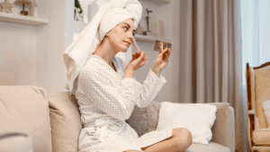 Mulher aplica maquiagem com pincel em frente ao espelho, representando o uso cotidiano de produtos de beleza e sua possível relação com a infertilidade.