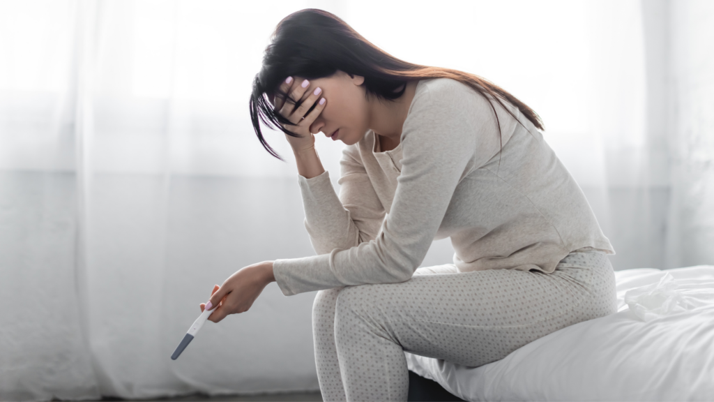 Mulher angustiada segurando teste de gravidez negativo, ilustrando o impacto da saúde mental e fertilidade.