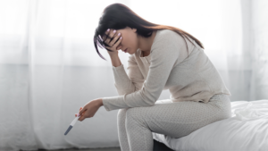 Mulher angustiada segurando teste de gravidez negativo, ilustrando o impacto da saúde mental e fertilidade.